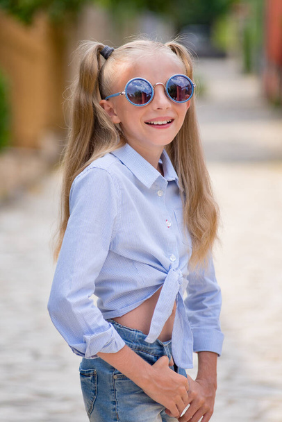 Ritratto di una ragazza felice in vacanza. ragazza in occhiali da sole e con lunghi capelli biondi sorride. - Foto, immagini