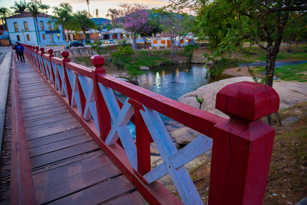 Most Carmo w mieście Pirenpolis w Gois nad Rio das Almas, wykonane z drewna i malowane w kolorze czerwono-białym. Muzeum Boskości w tle. Uważany za jedną z miejskich pocztówek. - Zdjęcie, obraz