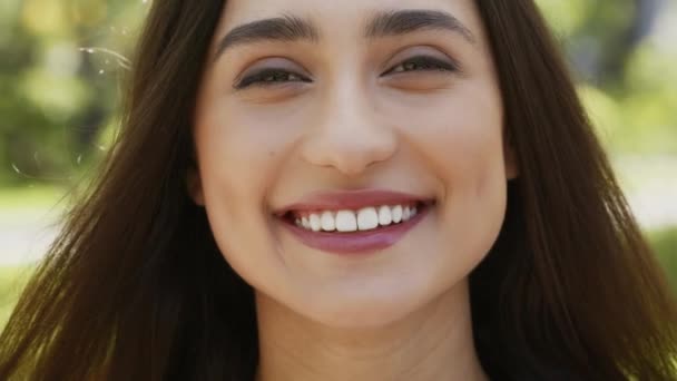 Ευτυχισμένη ελκυστική νεαρή γυναίκα χαμογελώντας κοιτάζοντας κάμερα στέκεται έξω - Πλάνα, βίντεο