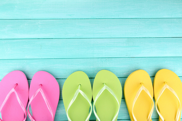 Bright flip-flops on color wooden background - Fotoğraf, Görsel