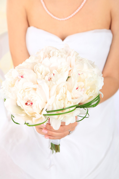 Bride holding wedding bouquet of white peonies, close-up, on light background - Zdjęcie, obraz