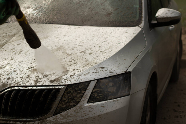 Car wash. The car is washed under the pressure of a jet of water. Using a water spray to wash off dirt from the surface of the car. - Φωτογραφία, εικόνα