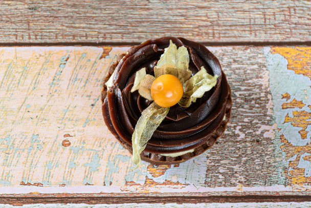 Primer plano de mini pastel con crema de mascarpone y ganache de chocolate, decorado con physalis (vista superior). - Foto, Imagen