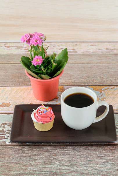 Крупный план мини-пирога с выпечкой Sablee и взбитыми сливками, рядом с чашкой кофе и растением. - Фото, изображение
