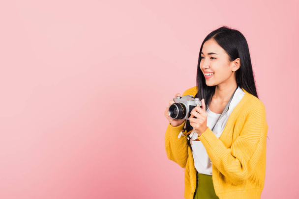 Attractive happy Asian portrait lifestyle beautiful young woman excited smiling photographer holding retro vintage photo camera ready to shoot isolated on pink background, tourism and vacation concept - 写真・画像