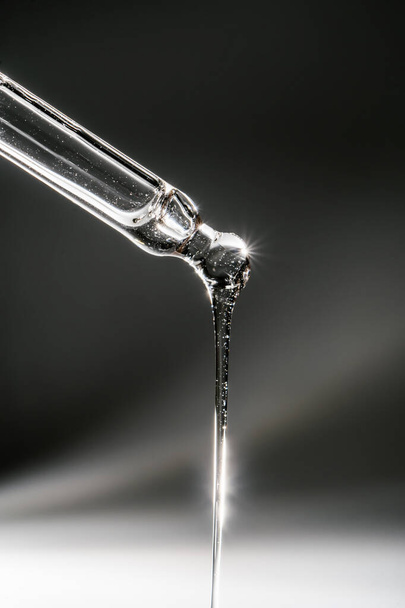 A drop of cosmetic oil falls from the pipette - Foto, imagen