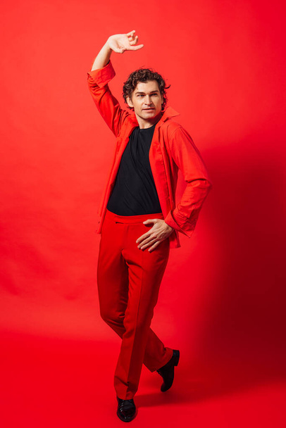 Portrait of a tall handsome man dressed in red shirt posing on the red background. - Valokuva, kuva