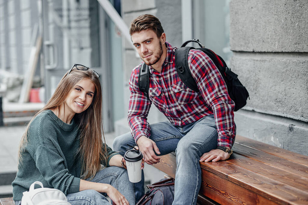 Young couple with coffee sitting and talking in a city. - 写真・画像
