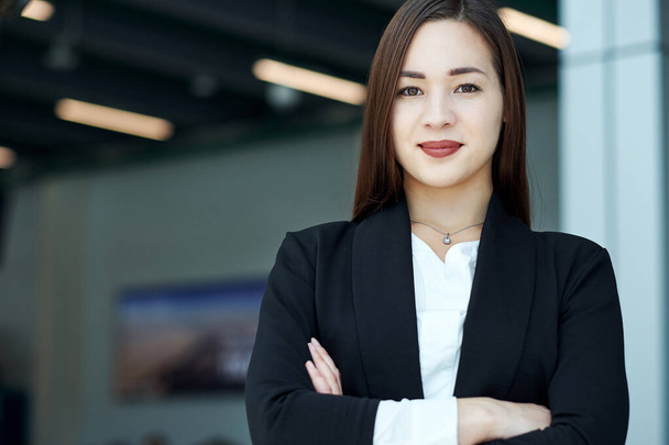Mujer de negocios asiática sonriente en oficina moderna o sala de reuniones. brazos cruzados - Foto, Imagen