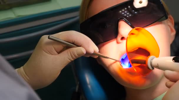 Dentista fijación de llenado de luz utilizando fotopolímero lámpara sin cuerda dental. El médico enciende la luz ultravioleta dentro de la boca de los pacientes. Odontología moderna. Parte final del tratamiento dental. 4 k vídeo - Metraje, vídeo