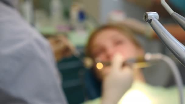 Dentista examinando dentes com instrumentos médicos. Filmagem desfocada através de ferramentas dentárias. Uma jovem a ter os dentes tratados. Tratamento dentário. Estomatologia médica moderna. 4 k vídeo - Filmagem, Vídeo