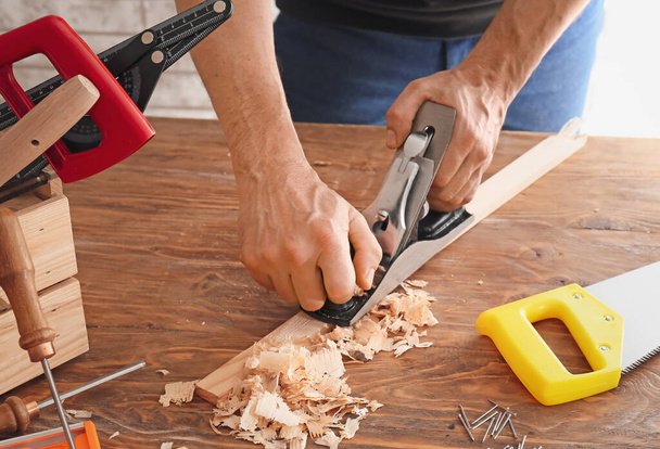 Carpenter planing plank on wooden table, closeup - Photo, Image