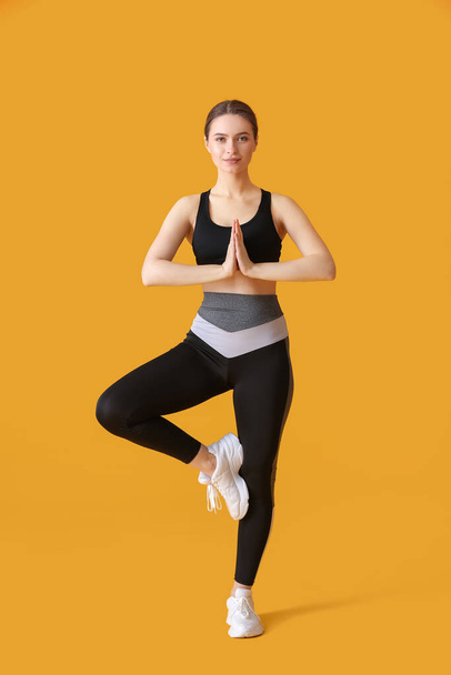 Sportieve jonge vrouw doet yoga op kleur achtergrond - Foto, afbeelding