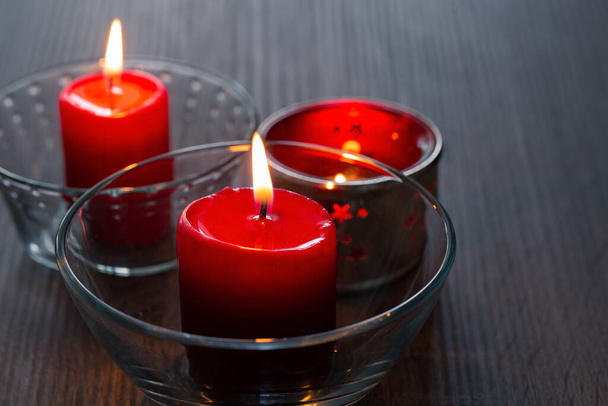 Τρία κόκκινα κεριά σε κοντινό πλάνο. Είδη διακόσμησης σπιτιού. Φωτεινό φως από κεριά που καίγονται, πλαϊνή άποψη - Φωτογραφία, εικόνα