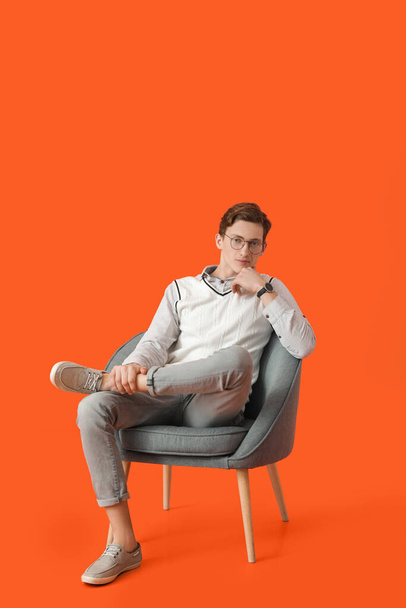 Young man sitting in armchair on color background - Фото, зображення