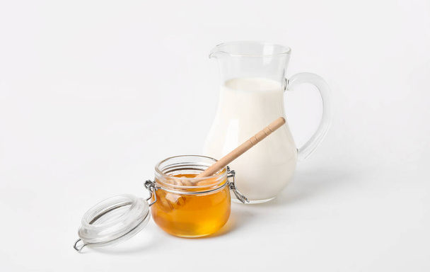 Стеклянная банка со сладким медом кувшин молока на белом фоне - Фото, изображение