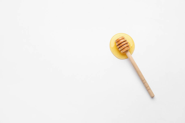 Wooden dipper and spilled honey on white background - Φωτογραφία, εικόνα