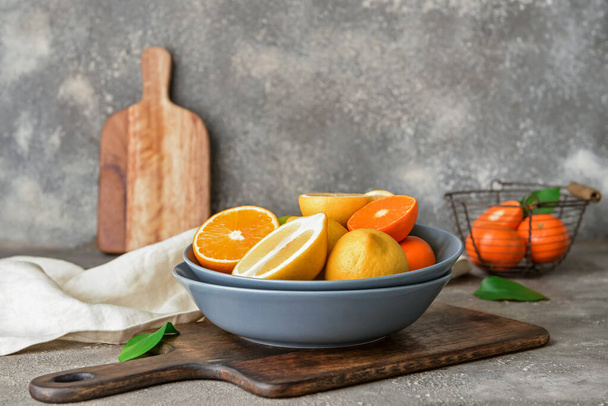 Bowl with healthy citrus fruits on grey background - Fotó, kép