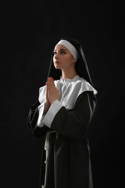 Young praying nun on dark background - Valokuva, kuva