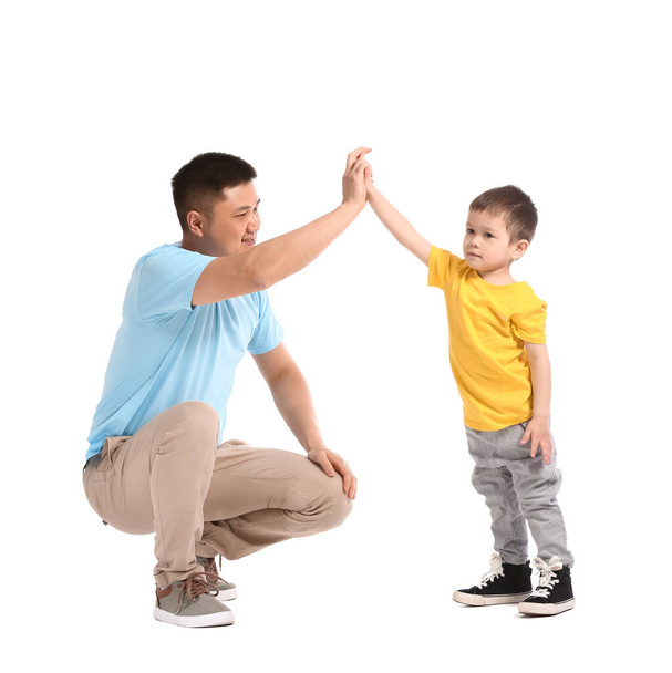 Happy father and his little son giving each other high-five on white background - Photo, image