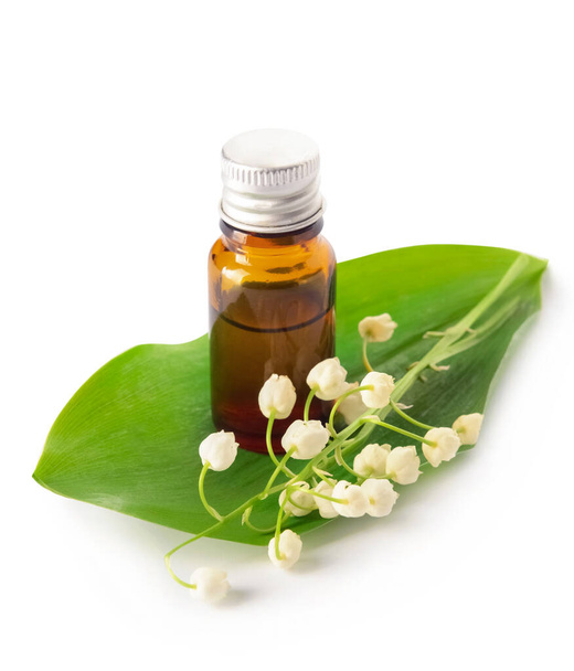 Bottle with essential oil and lily-of-the-valley flowers on white background - 写真・画像