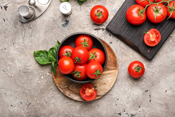 Schüssel mit frischen reifen Tomaten, Gewürzen und Basilikumblättern auf Grunge-Hintergrund - Foto, Bild