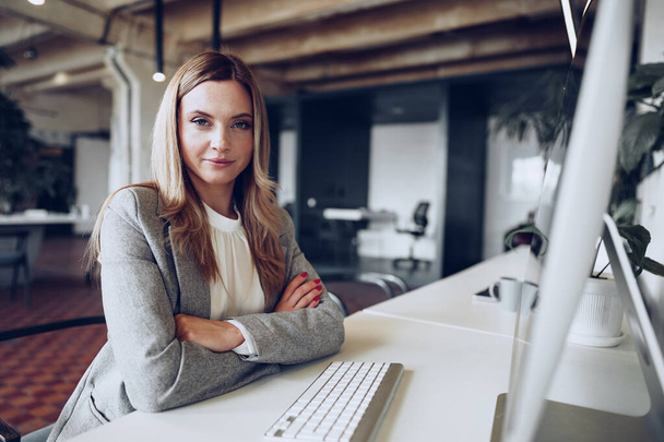 Portrait of a young smart businesswoman sitting at her working table in office - Valokuva, kuva