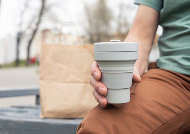Collapsible eco cup for takeaway coffee or tea. Male hand with sustainable silicon mug. Zero waste lifestyle - Foto, Imagen