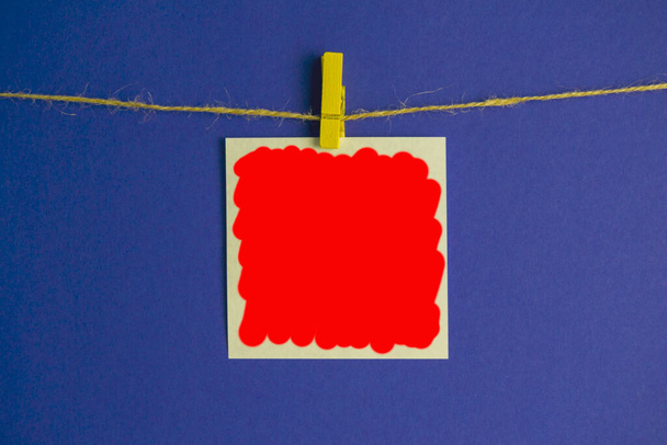 лист для заметок на прищепке на синем фоне. пустое место для записей, заполненных красным - Фото, изображение
