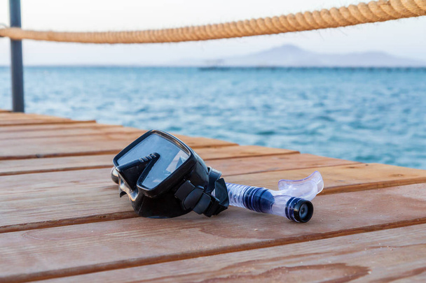 Tauchmaske und Schnorchel für Profis auf einem Holzsteg mit Meer im Hintergrund. Reise- und Urlaubskonzept. - Foto, Bild