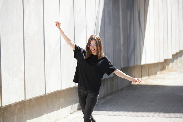 Woman or girl wearing black blank cotton t-shirt with space for your logo, mock up or design in casual urban style - Valokuva, kuva