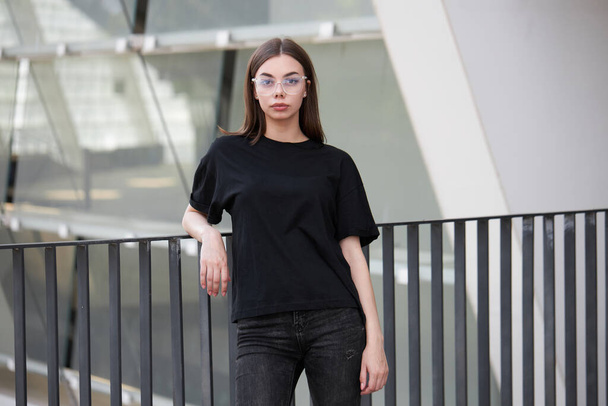 Woman or girl wearing black blank cotton t-shirt with space for your logo, mock up or design in casual urban style - Zdjęcie, obraz