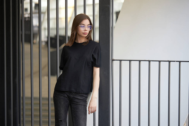 Woman or girl wearing black blank cotton t-shirt with space for your logo, mock up or design in casual urban style - Fotografie, Obrázek