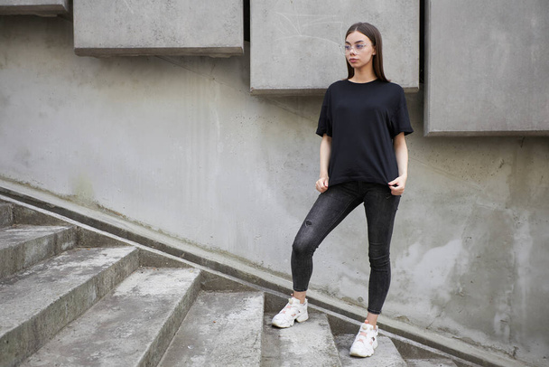 Woman or girl wearing black blank cotton t-shirt with space for your logo, mock up or design in casual urban style - Fotó, kép