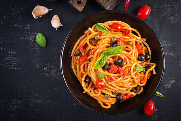 スパゲッティアッラ・プッタネスカ-トマトとイタリアのパスタ料理,黒オリーブ,ケッパー,アンチョビとバジル.トップビュー、フラットレイアウト - 写真・画像