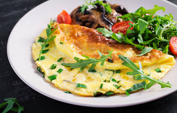 Omelette with cheese, green herbs and fried mushrooms on plate.  Frittata - italian omelet - Photo, Image