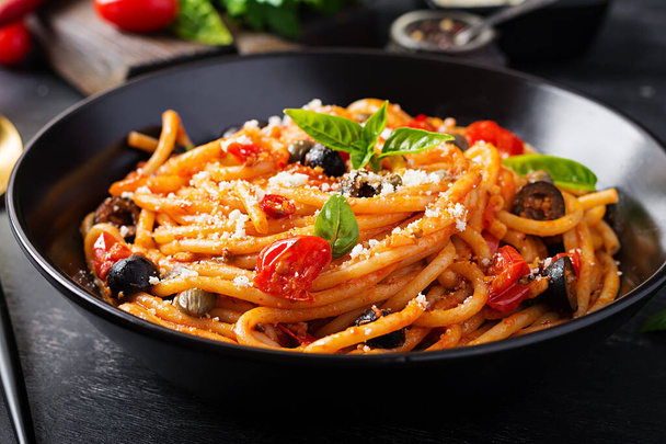 Spagetti alla puttanesca - olasz tészta paradicsom, fekete olajbogyó, kapribogyó, szardella és bazi - Fotó, kép