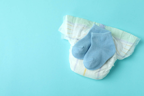 Diaper with baby socks on blue background - Фото, изображение
