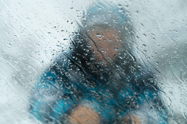 Desfoque a silhueta de um homem na janela com gotas de chuva - Foto, Imagem