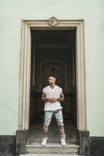 A vertical shot of a handsome male in casual clothes posing in front of an old building in Spain - Фото, изображение