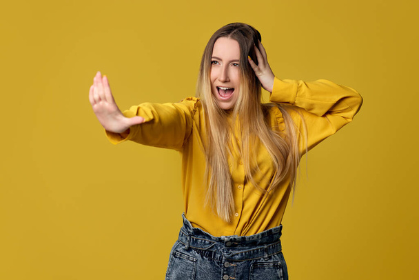 woman showing stop gesture on yellow background - Foto, immagini