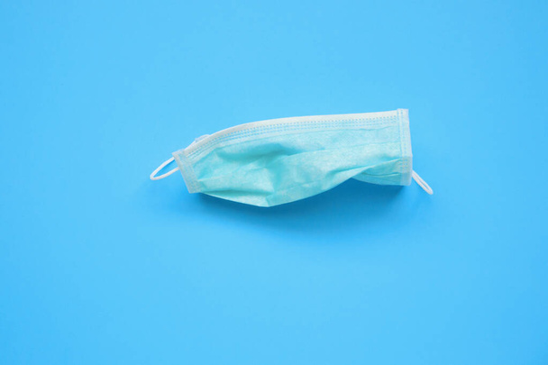 Disposable surgical face mask on blue background protection against COVID-19 coronavirus. Healthcare and medical concept - 写真・画像