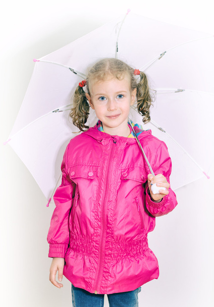 kleines Mädchen in hellem Mantel mit Regenschirm. drinnen. - Foto, Bild
