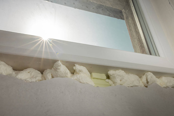 Detalle de espuma expansiva de poliuretano PU utilizada para fijar repisas de ventanas o estantes de mármol. Fijación del estante de ventana. - Foto, imagen