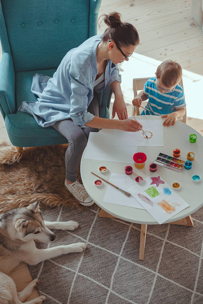 Mom and child paint together at home with a dog - Фото, изображение