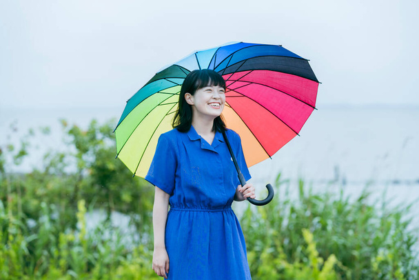Une femme tenant un parapluie coloré sous la pluie - Photo, image