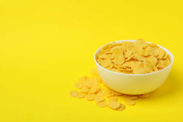 Schaal van cornflakes op gele achtergrond - Foto, afbeelding