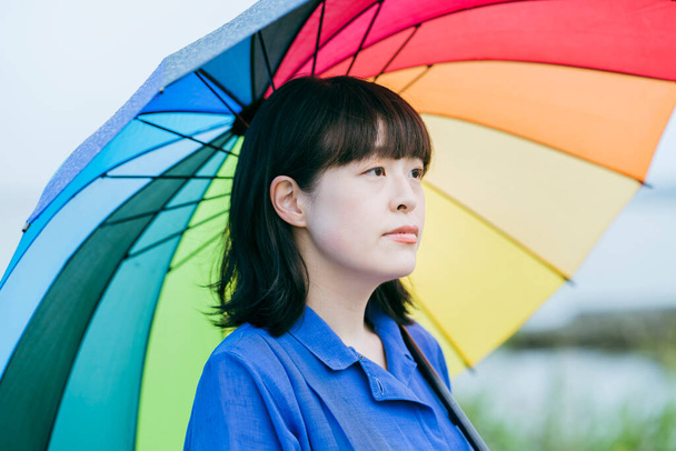 Nainen, jolla on värikäs sateenvarjo sateessa - Valokuva, kuva