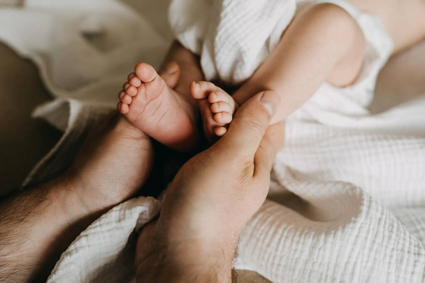 Father holding small newborn baby feet in hands. - Φωτογραφία, εικόνα