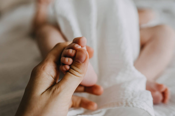 Primer plano de la madre sosteniendo el pequeño pie del bebé recién nacido. - Foto, imagen